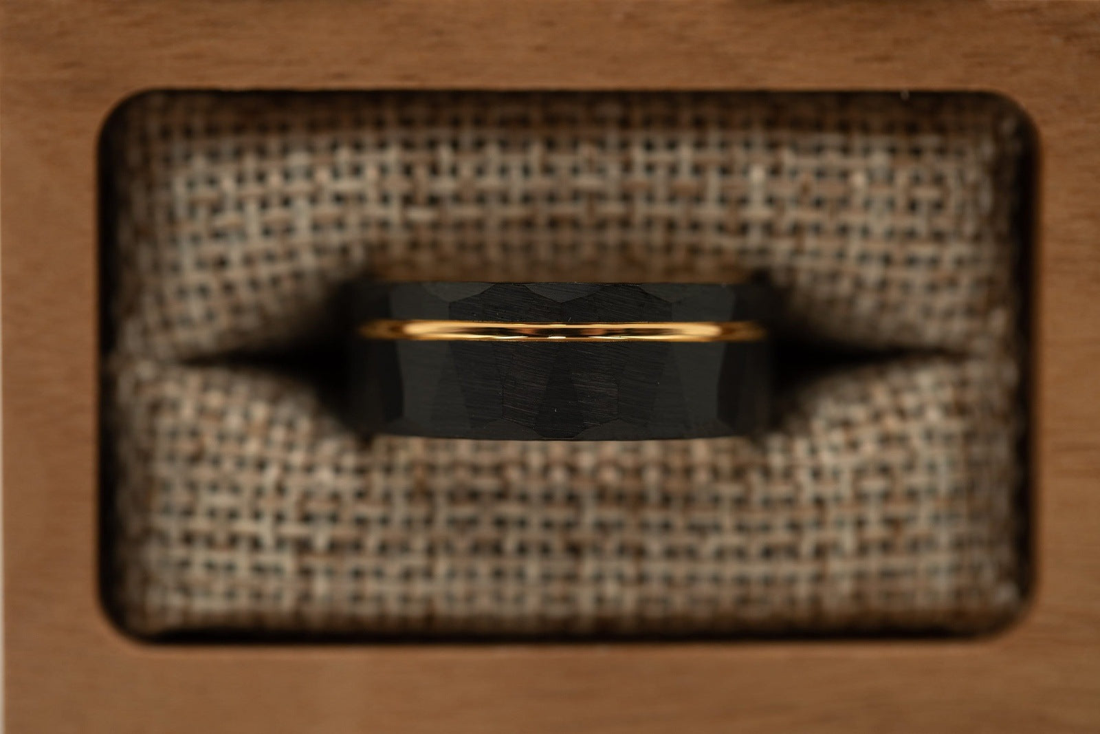 Hammered Black Tungsten Wedding Ring with Polished Rose Gold Inner Band inside walnut ring box between burlap cushions