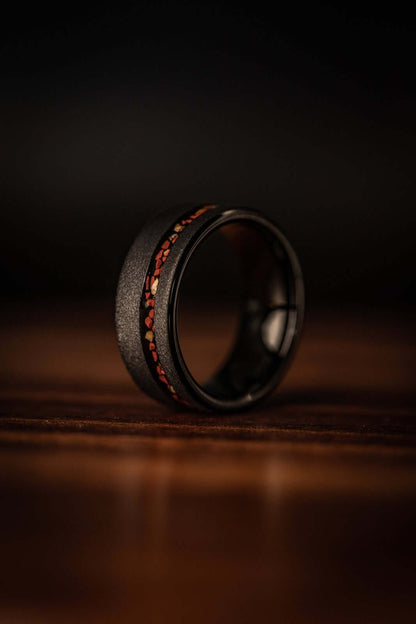 Distinctive wedding band featuring black sandblasted tungsten and striking red dinosaur bone.